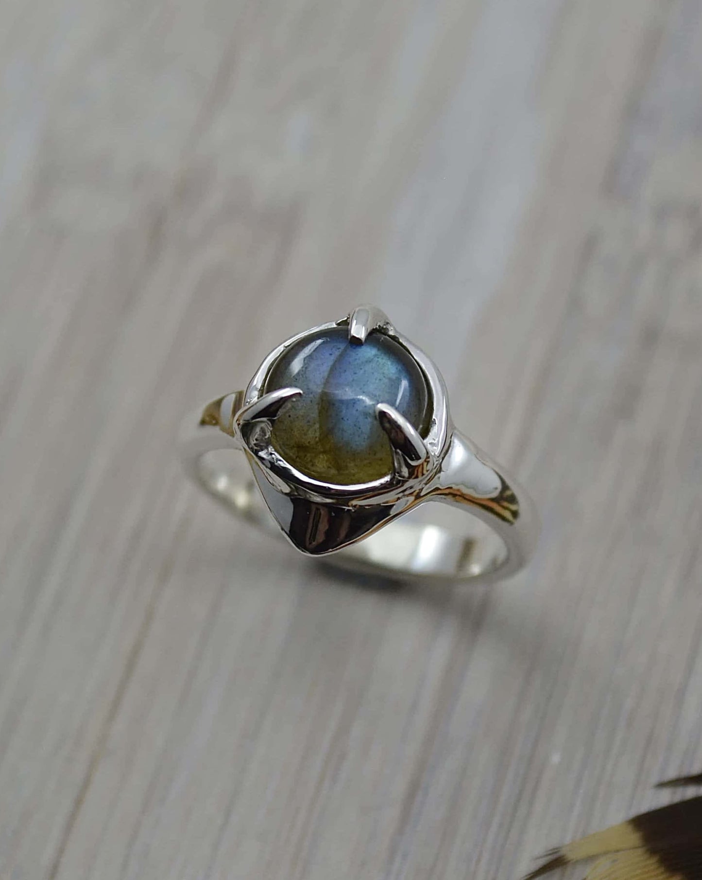 A sterling silver ring with a round labradorite stone set in the center, featuring a 'wobble' effect on the band.