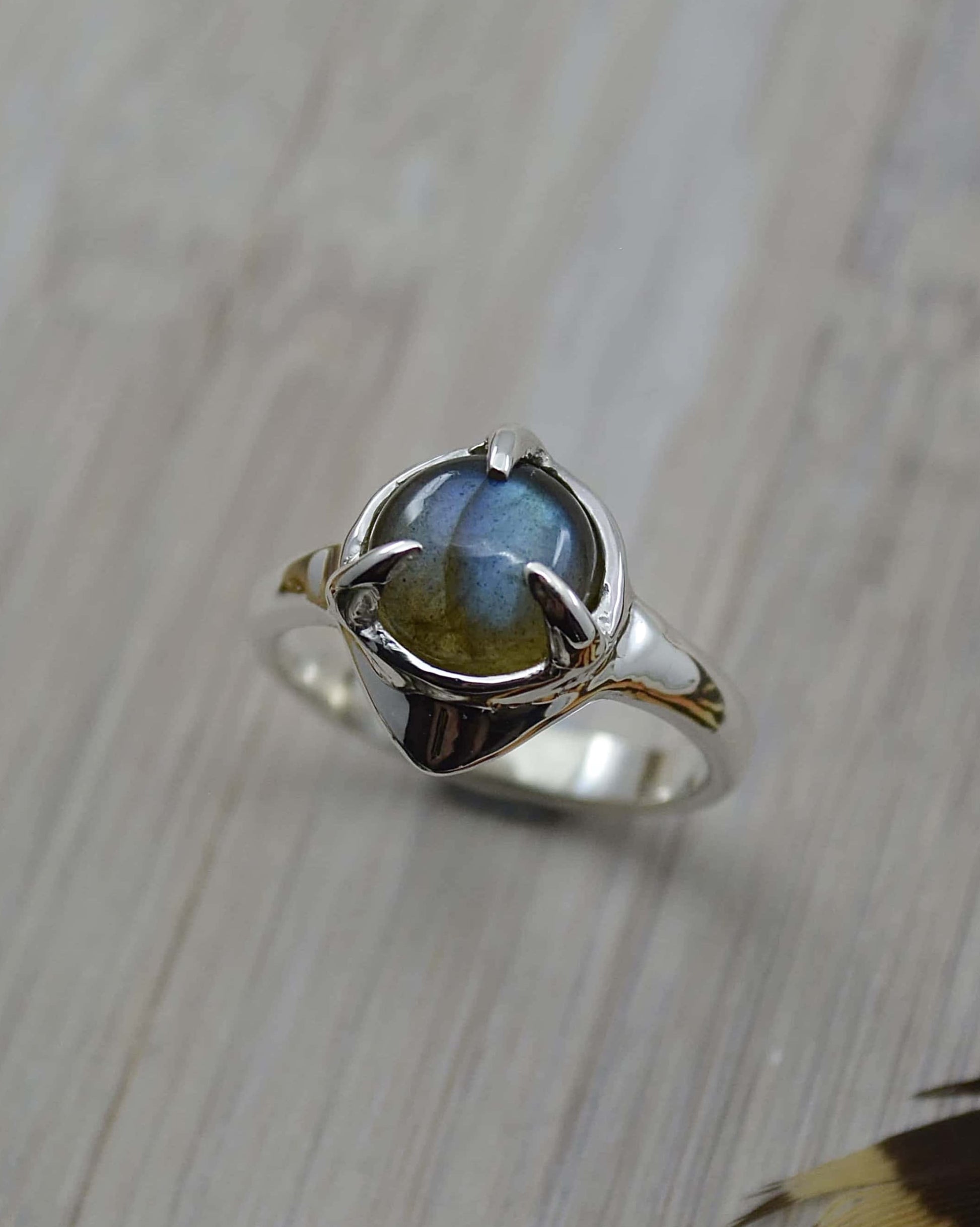 A sterling silver ring with a round labradorite stone set in the center, featuring a 'wobble' effect on the band.