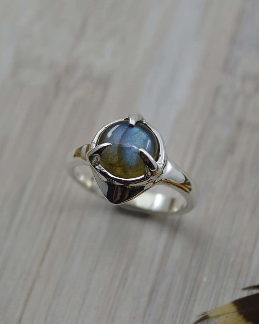 A sterling silver ring with a round labradorite stone set in the center, featuring a 'wobble' effect on the band.