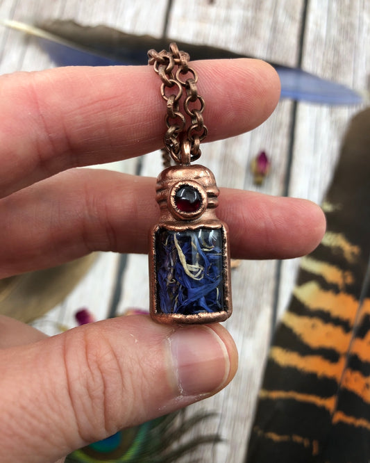 copper glass bottle pendant with cornflower blue flower petals and garnet stone